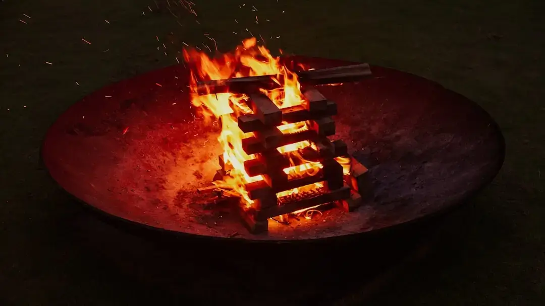 A fire burns in a round metal fire pit.