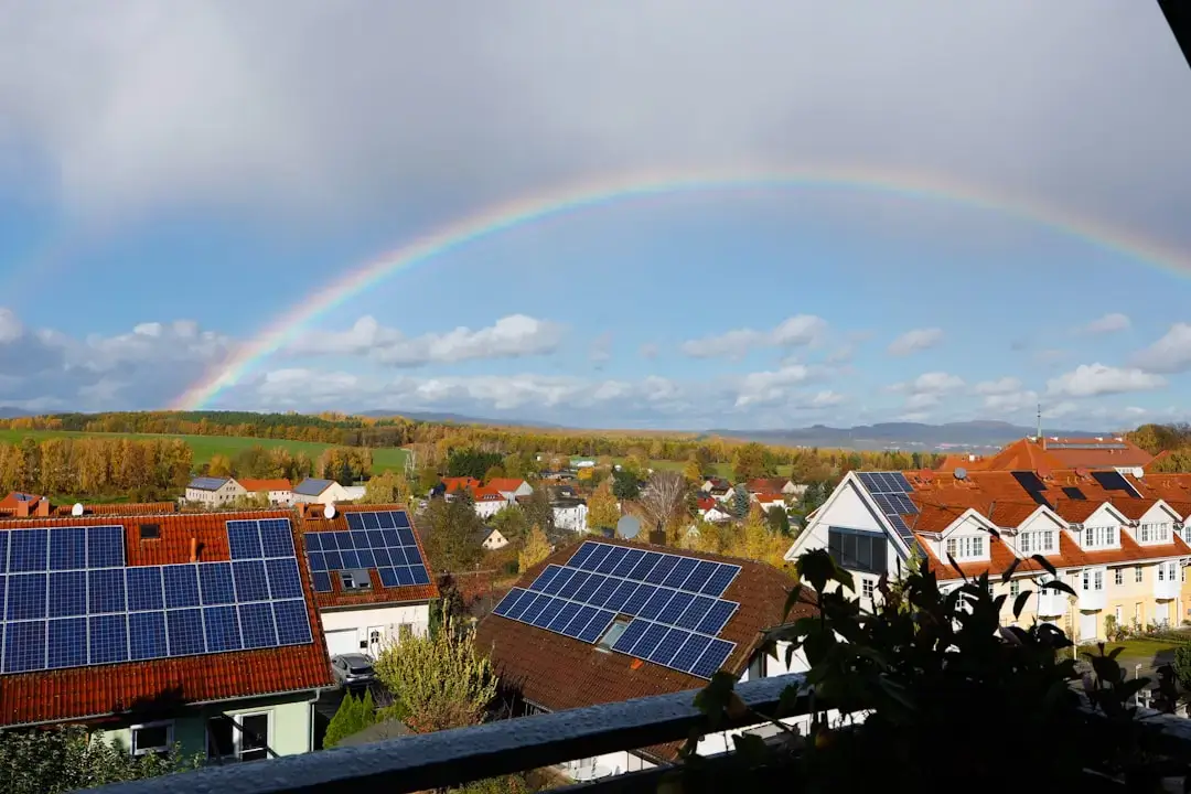 Rainbow over a suburban neighborhood with solar panels.
