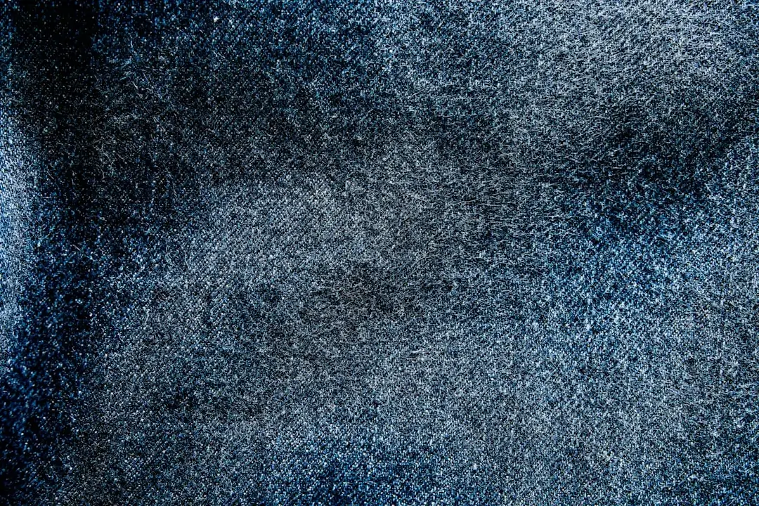Detailed close-up shot of blue jeans fabric showing the woven denim texture and thread patterns.