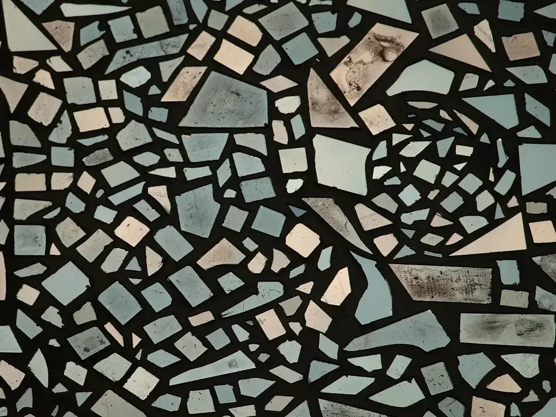 Close-up of broken ceramic plate pieces with white and blue textures scattered on a neutral surface