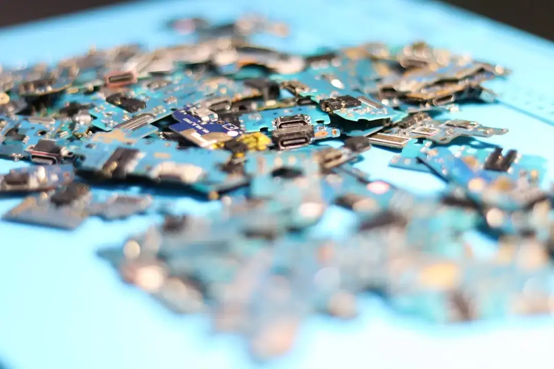 Broken circuit boards are scattered on a blue surface.
