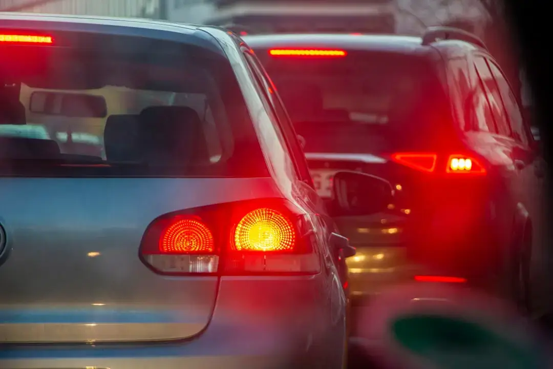 A long line of cars and buses stuck in heavy traffic on a multi-lane city highway during rush hour.