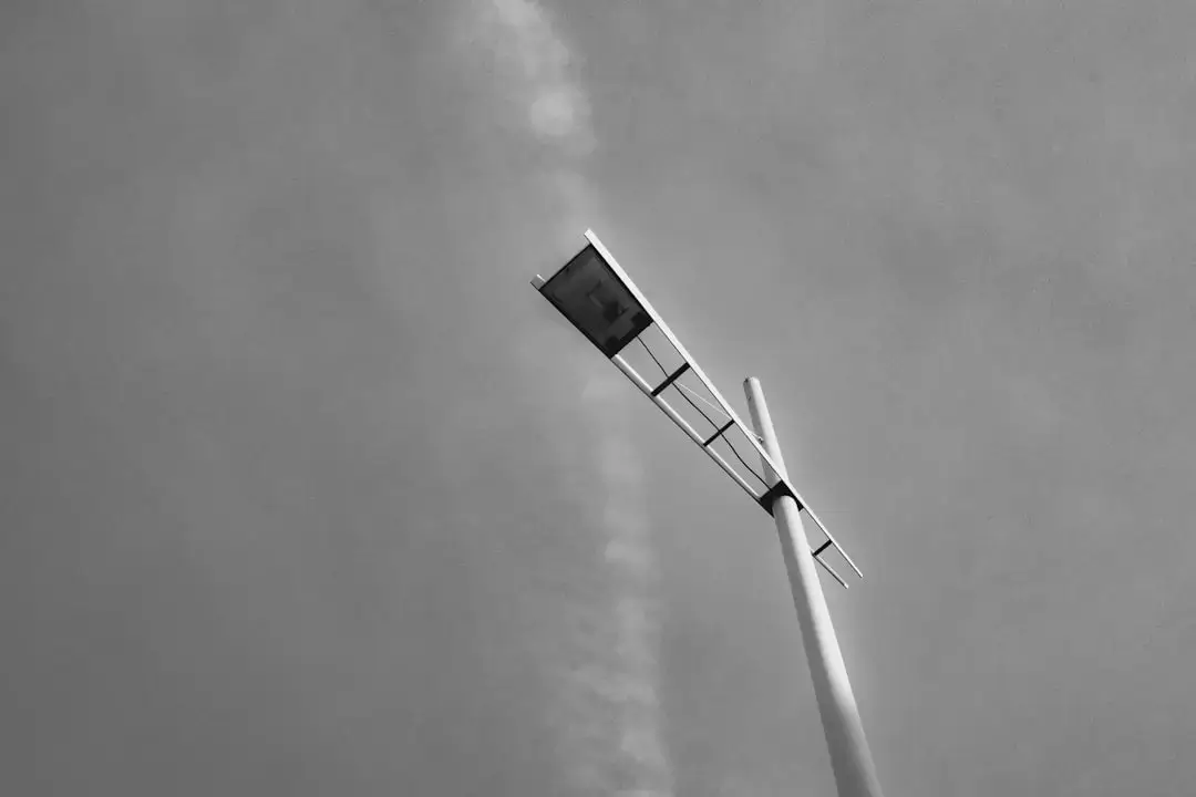 A detailed close-up shot of the sleek white surface and curve of a modern wind turbine blade against a clear sky.
