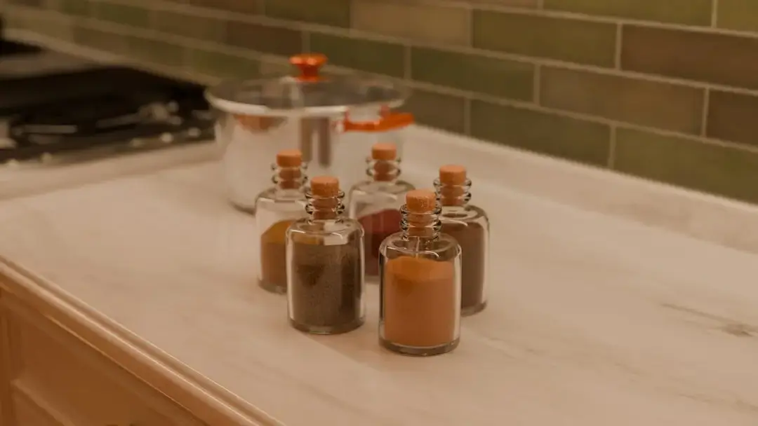 An assortment of vibrant, colorful powdered spices and herbs neatly arranged in clear glass jars on a kitchen counter.