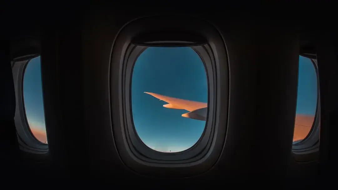 A commercial passenger airplane soaring through a vibrant orange and purple sky during a scenic sunset.