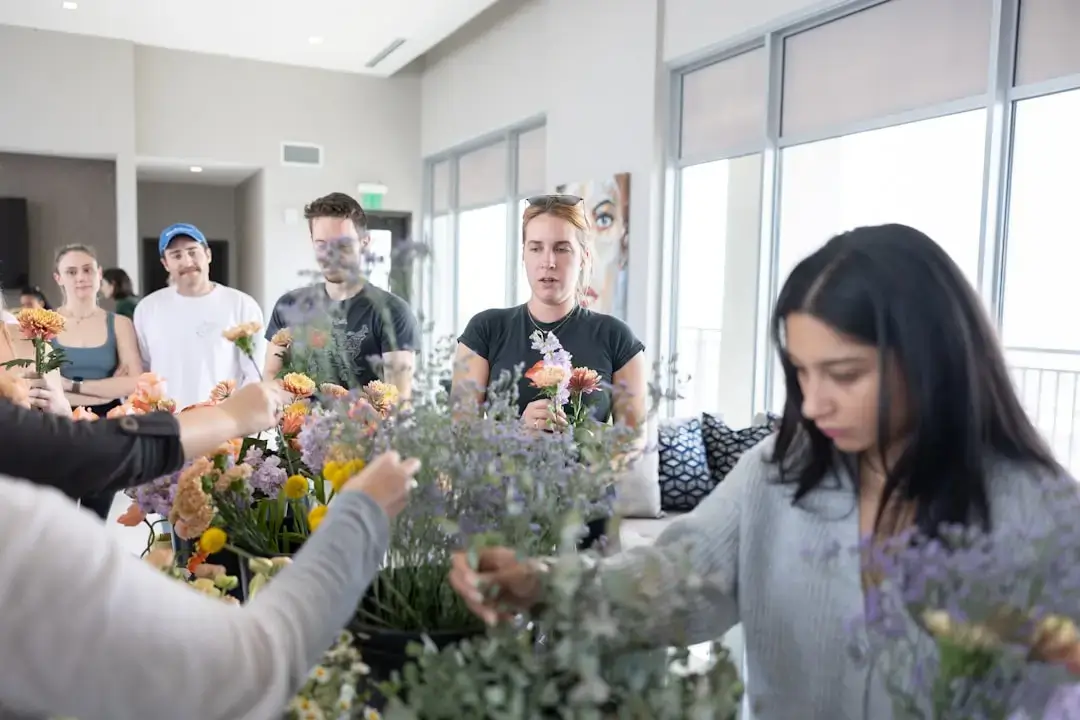 A group of diverse volunteers working together to plant young tree saplings in a grassy field for a reforestation project.