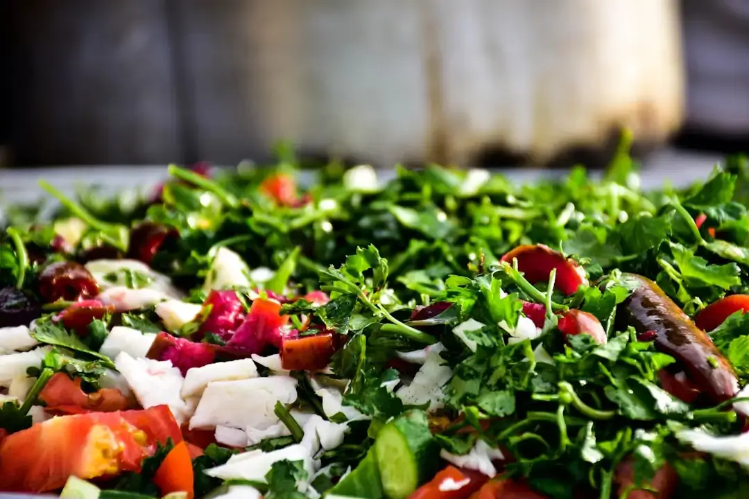 A rustic bowl of vibrant green arugula pesto garnished with pine nuts and fresh leaves on a wooden table
