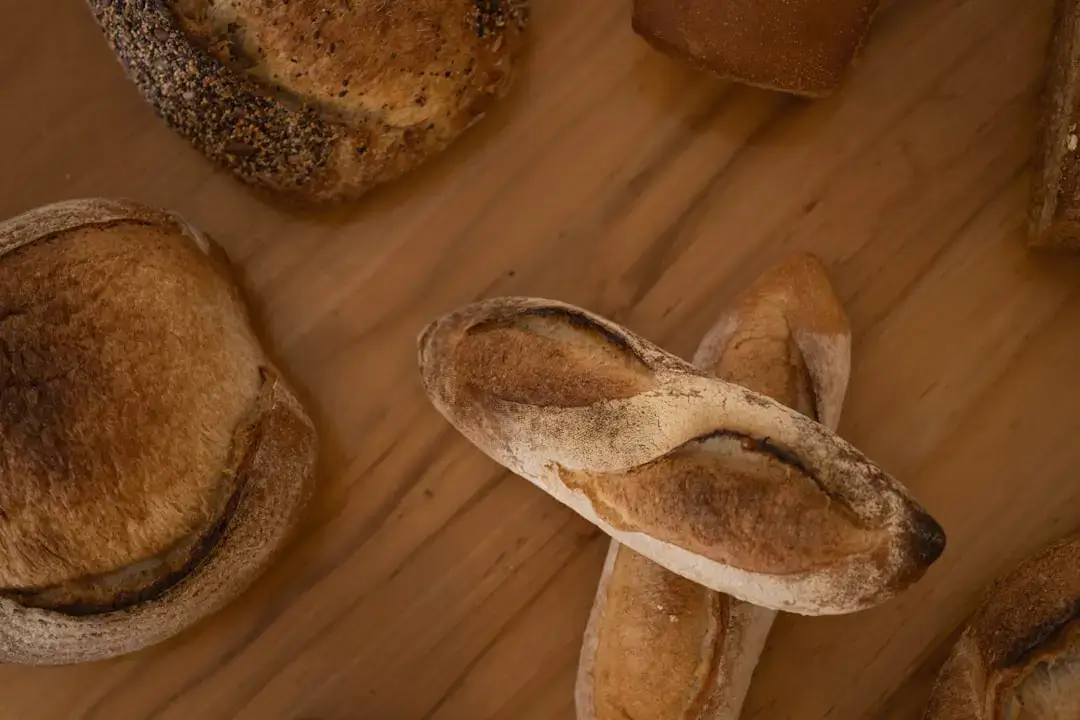 A loaf of freshly baked crusty sourdough bread resting on a rustic wooden cutting board.