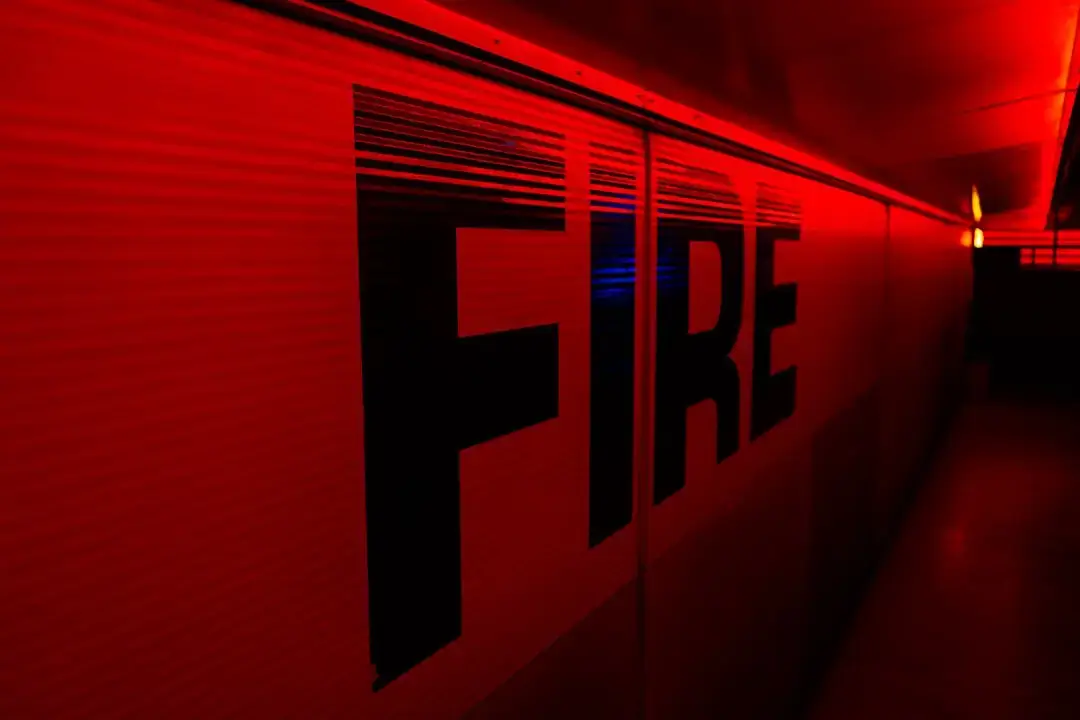 A bright yellow industrial triangle warning sign indicating critical fire hazard precautions in a workplace environment.