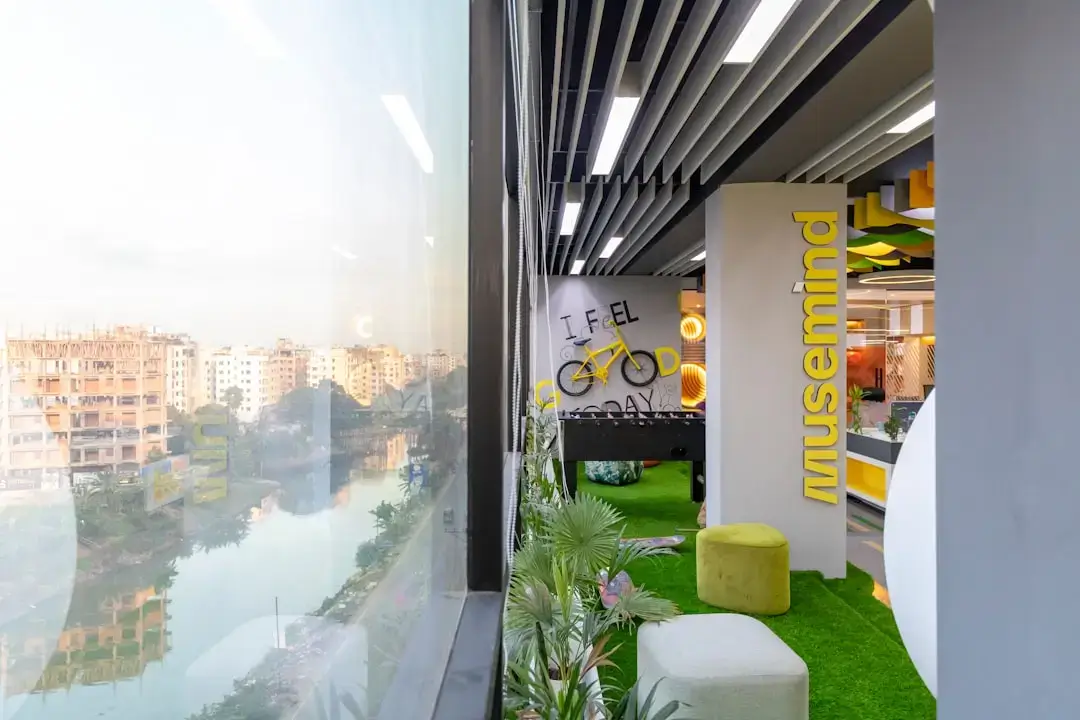A contemporary white and green office space featuring indoor plants, natural light, and sustainable wooden furniture.