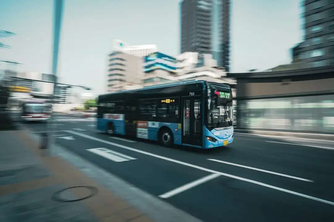 A modern hydrogen fuel cell bus driving on a city street, representing clean energy public transportation.