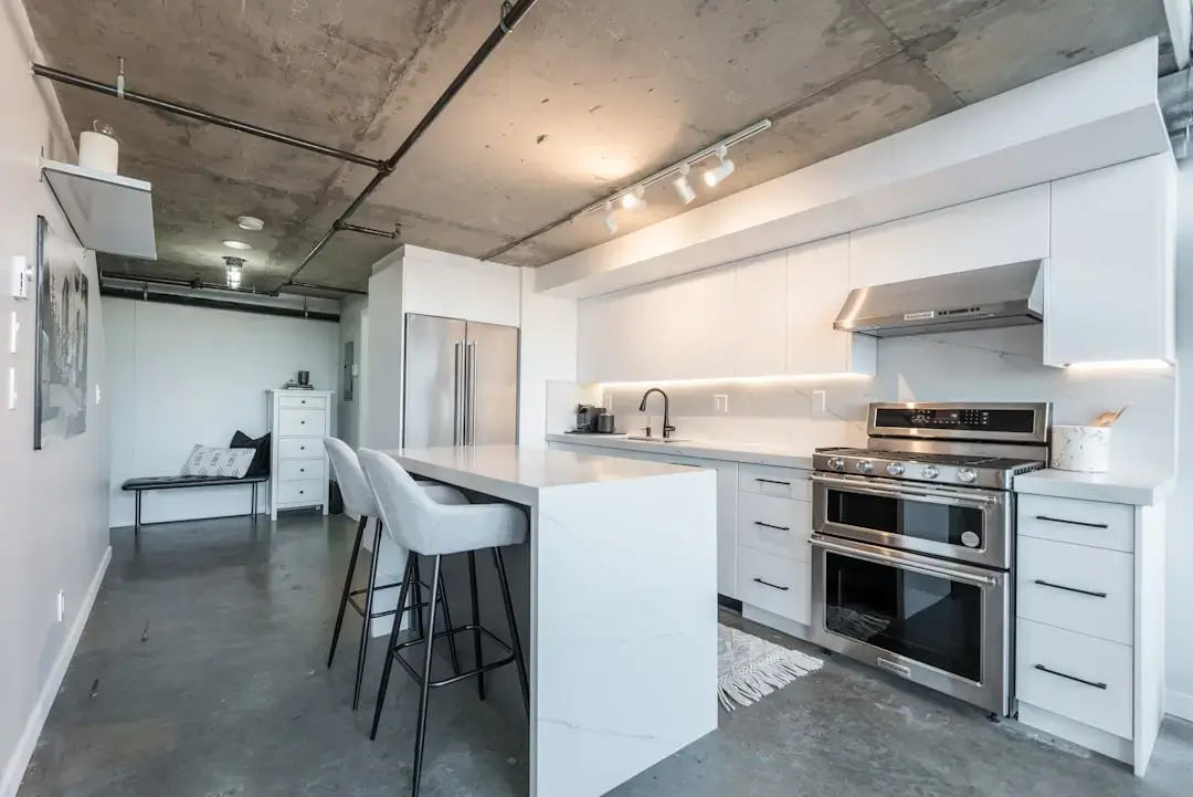 A sleek and modern kitchen featuring an integrated stainless steel dishwasher built into minimalist white cabinets.