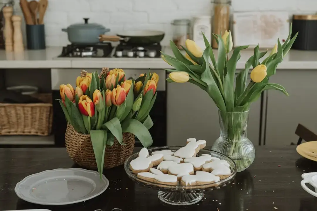 An elegant rustic wooden table set for Easter dinner with pastel plates, linen napkins, and spring floral decorations.