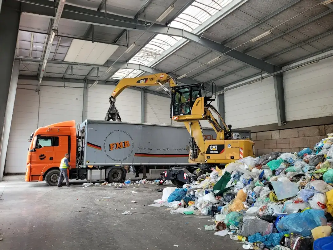 A person hands putting plastic and paper items into separate recycling bins to sort mixed waste.