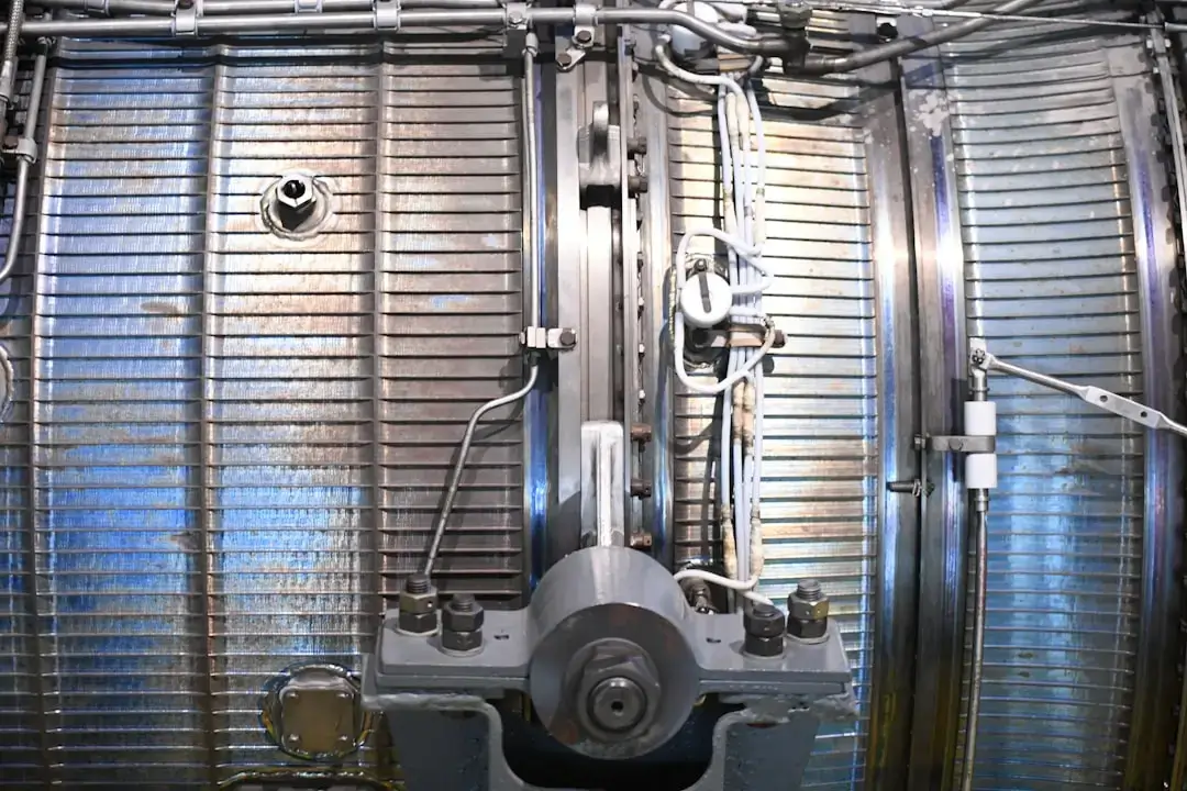 A professional technician carefully cleaning metal mechanical components at a workbench in a bright industrial workshop.
