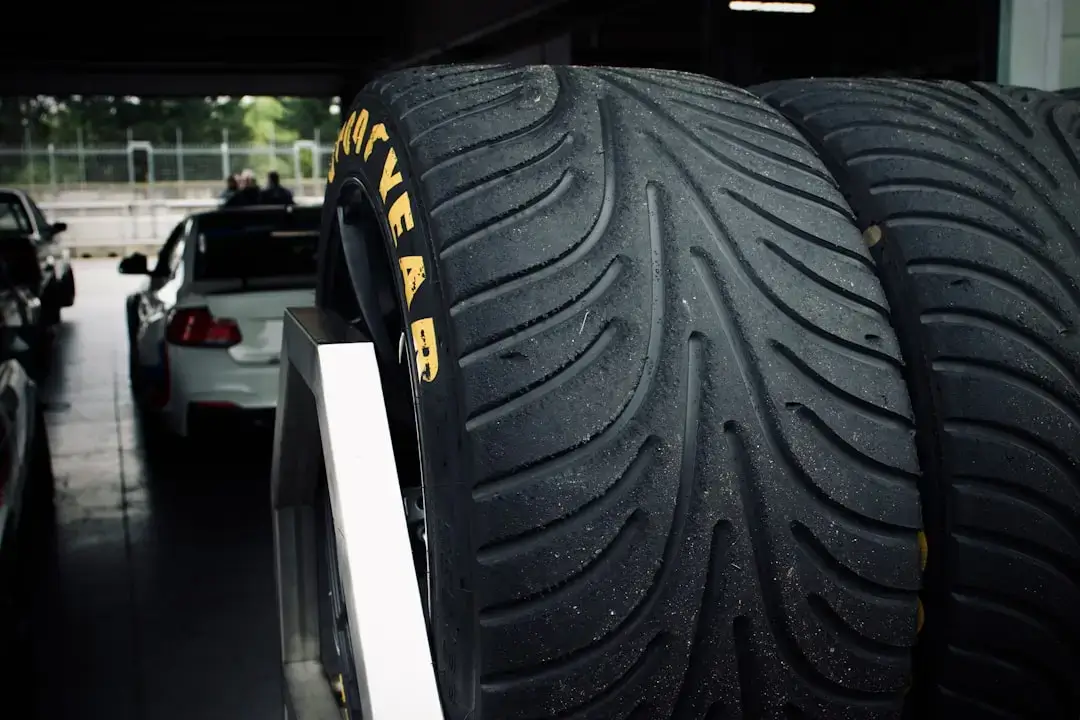 A large stack of used black car tires being organized for sustainable environmental recycling at an industrial plant.