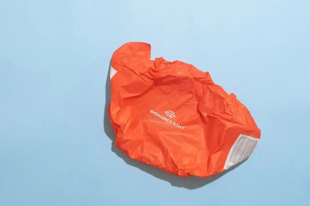 Close-up of a person properly removing and disposing of a full dust bag from a vacuum cleaner to maintain suction.