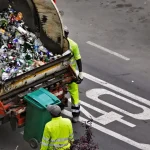 people collecting trash in garbage truck