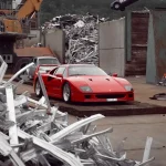 Red ferrari sports car in a junkyard.