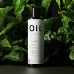 a bottle of oil sitting on top of a lush green plant