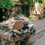 A man pushing a cart full of items down a street