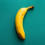 a ripe banana sitting on top of a green surface