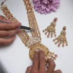 A woman is working on a gold necklace