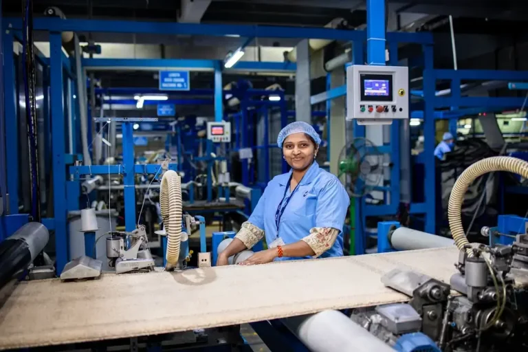 Factory worker smiles while operating machinery.