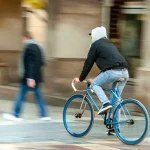 man in black jacket riding blue bicycle on road during daytime