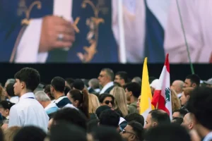 A crowd watches a large screen at an event.