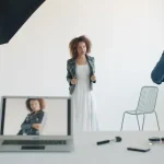 Model posing in studio with photographer and equipment