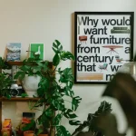 A room with plants, shelf, and a framed quote.