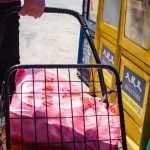 A close-up of folded second-hand clothes being prepared for a clothing donation bin.