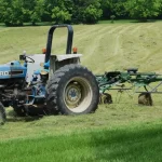 A close up of a tractor mounted boom sprayer or garden tractor attachment working on green grass