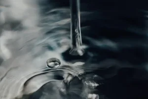Close-up of hands turning off a sleek bathroom faucet to conserve water and prevent waste.
