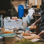 A person preparing fresh vegetables on a wooden cutting board to prevent food waste in a sustainable kitchen