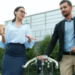 Two business professionals discuss near a bicycle.