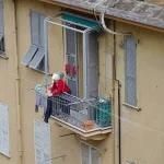 A small rainwater harvesting setup with a watering can on a cozy green apartment balcony