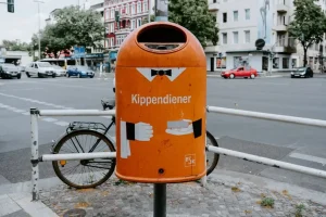 A green metal container for used clothing and textile recycling standing outdoors.