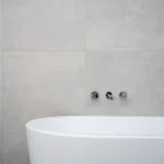 A modern chrome bathroom faucet mounted on a clean ceramic sink, representing plumbing hardware disposal.