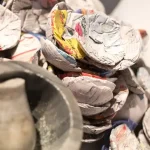 Close-up of grocery store receipts held in hand over colorful recycling bins, illustrating proper waste segregation.