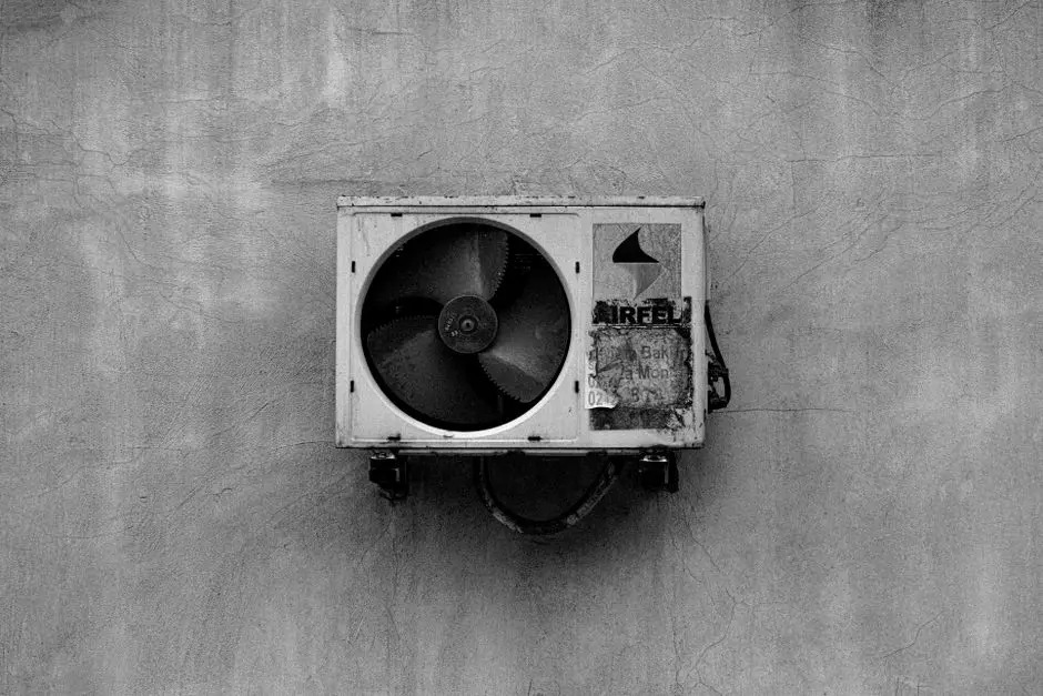 Monochromatyczny obraz klimatyzatora montowanego na ścianie na betonowej powierzchni.