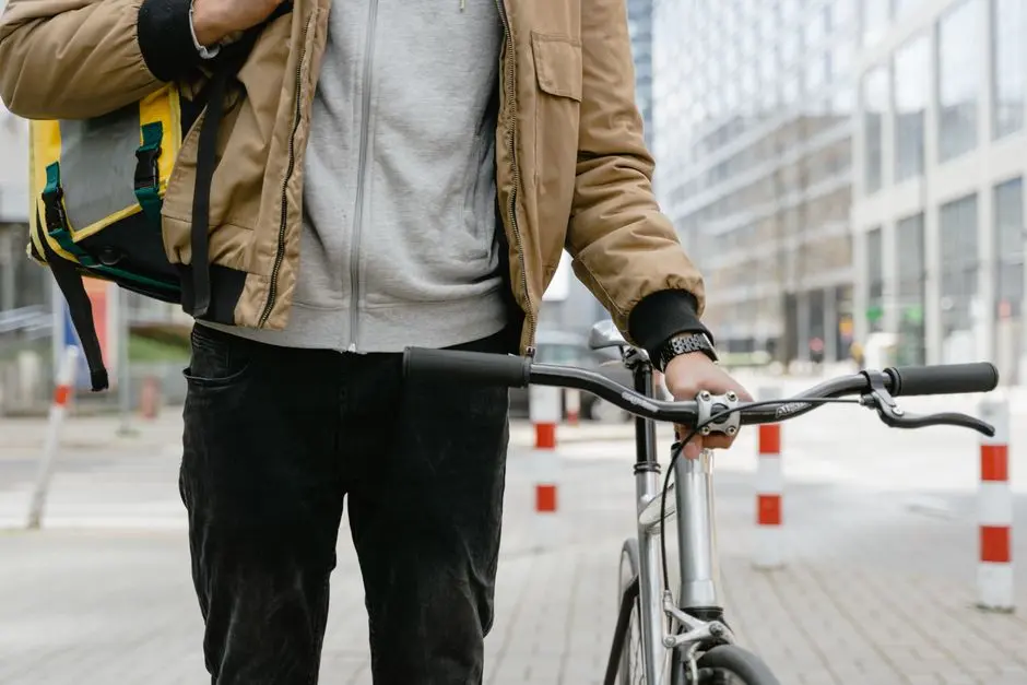 Kurier rowerowy stojący z rowerem w miejskim otoczeniu, gotowy do dostawy.