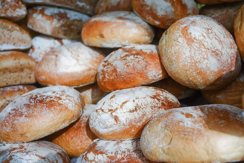 Zbliżenie na świeże, chrupiące bochenki chleba rzemieślniczego pokryte mąką, będące świadectwem kunsztu piekarskiego.