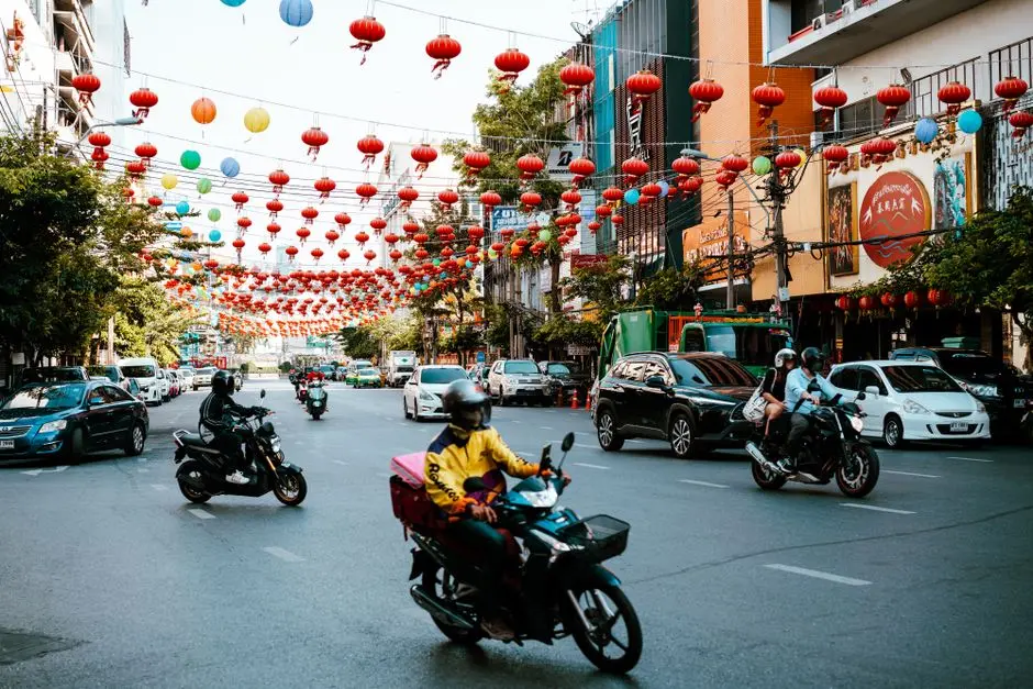 Miejska ulica tętniąca życiem z motocyklami pod festiwalowymi lampionami w świetle dziennym.