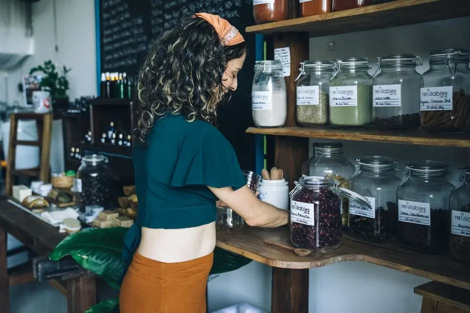Kobieta wybierająca organiczne produkty w uzupełnianym słoiku w ekologicznym sklepie spożywczym.